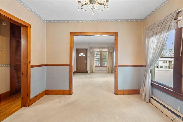 carpeted empty room featuring an inviting chandelier and a baseboard radiator