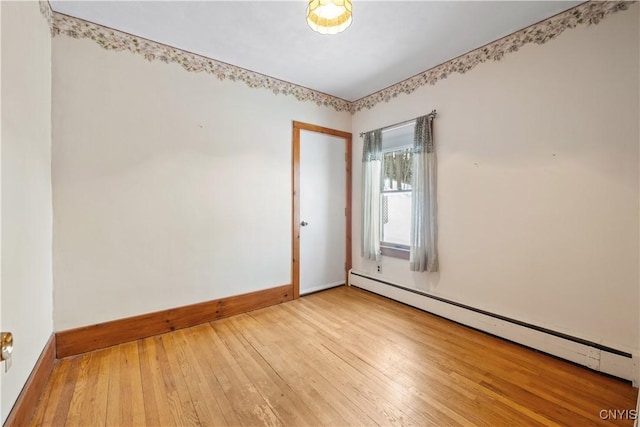 empty room featuring a baseboard radiator and light hardwood / wood-style floors