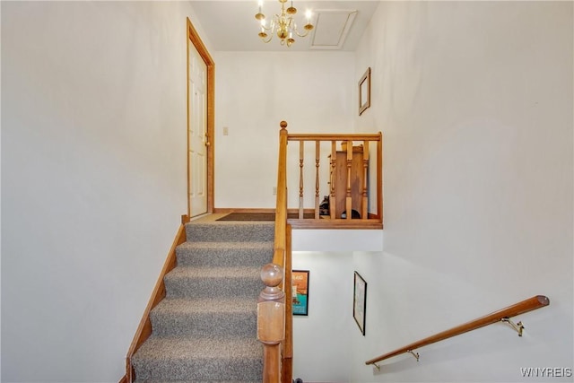 staircase featuring an inviting chandelier and carpet