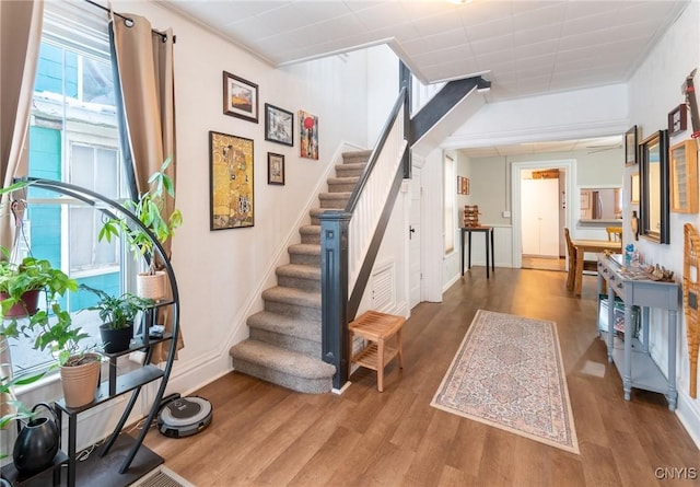 stairs with wood-type flooring and ornamental molding