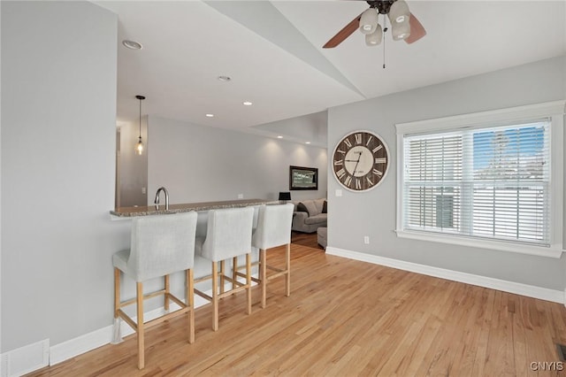 kitchen featuring light hardwood / wood-style floors, hanging light fixtures, a kitchen breakfast bar, and kitchen peninsula