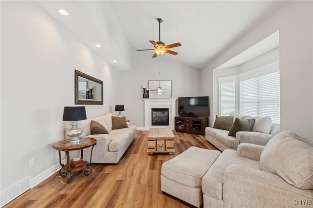 living room with ceiling fan, lofted ceiling, and light hardwood / wood-style flooring