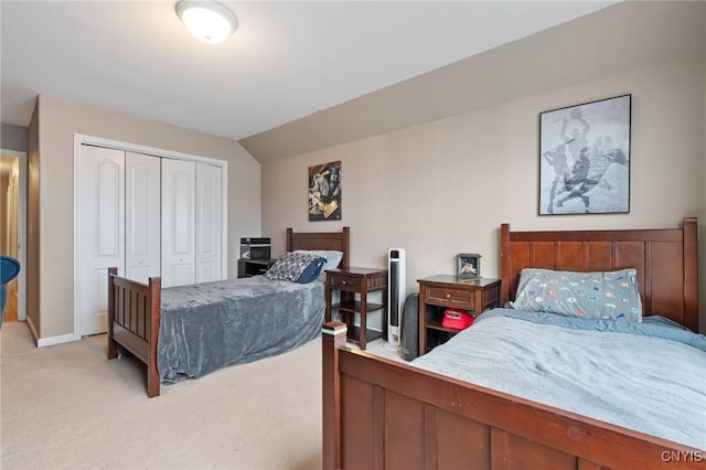 bedroom with vaulted ceiling, light colored carpet, and a closet