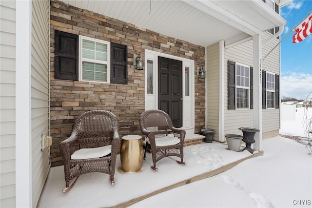 snow covered property entrance featuring covered porch