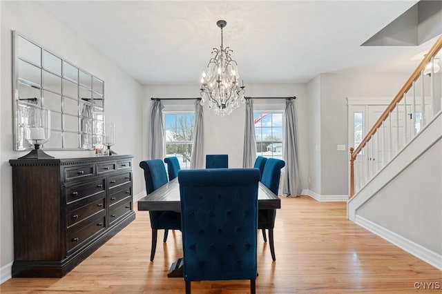 dining space with light hardwood / wood-style flooring and a notable chandelier