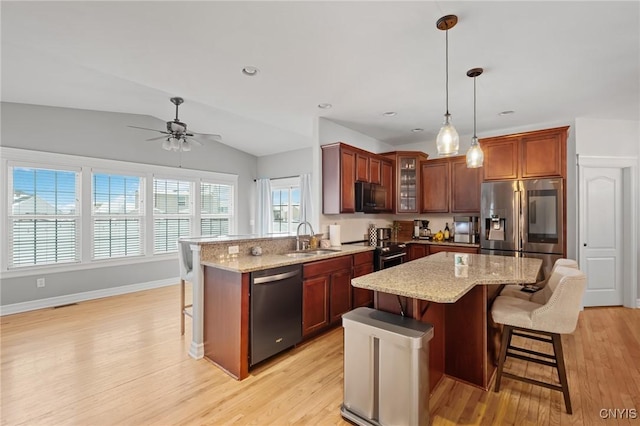 kitchen with stainless steel appliances, sink, a kitchen breakfast bar, and decorative light fixtures