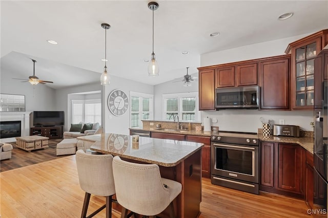 kitchen with sink, decorative light fixtures, appliances with stainless steel finishes, a kitchen breakfast bar, and a wealth of natural light