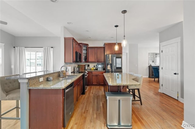 kitchen featuring sink, a breakfast bar area, stainless steel appliances, decorative light fixtures, and kitchen peninsula