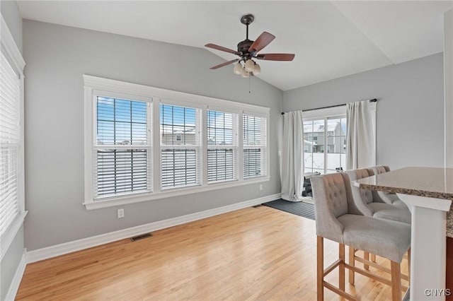 dining room with wood-type flooring, ceiling fan, and vaulted ceiling