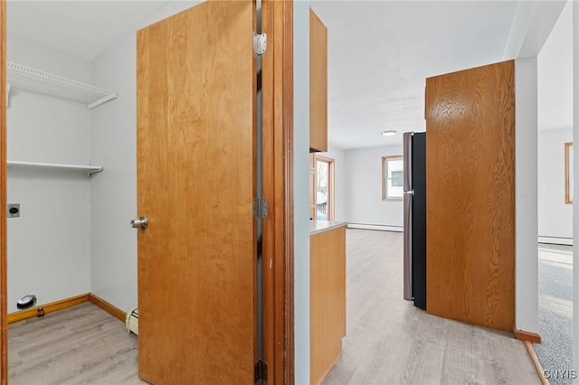 hall featuring a baseboard radiator and light hardwood / wood-style floors