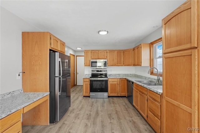 kitchen with light stone counters, appliances with stainless steel finishes, sink, and light wood-type flooring