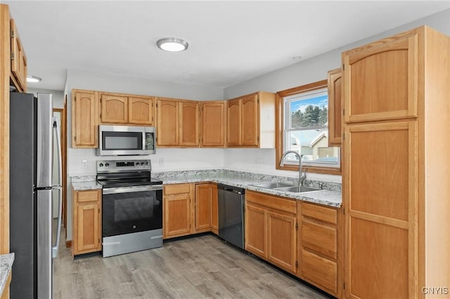 kitchen featuring light stone counters, stainless steel appliances, sink, and light hardwood / wood-style flooring