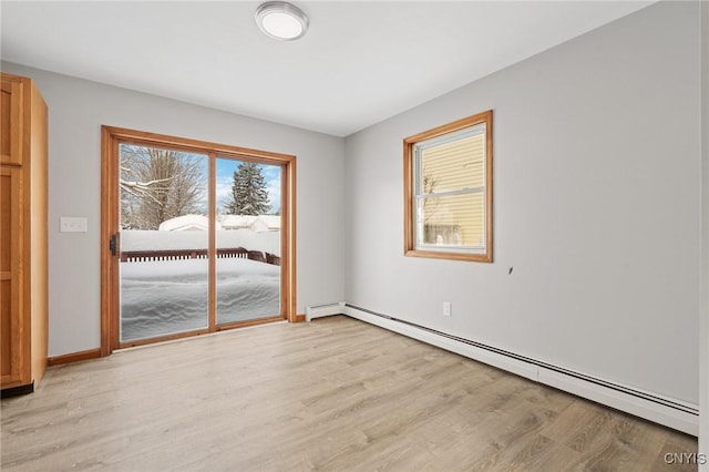 spare room featuring a baseboard heating unit and light hardwood / wood-style flooring