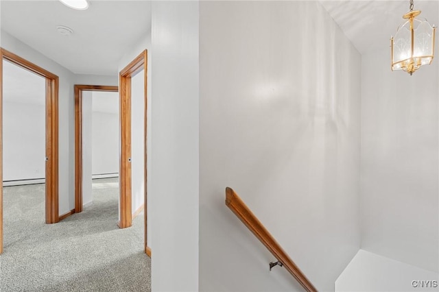 corridor featuring light carpet, a baseboard radiator, and an inviting chandelier