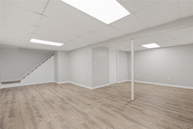 basement with a drop ceiling and light hardwood / wood-style flooring