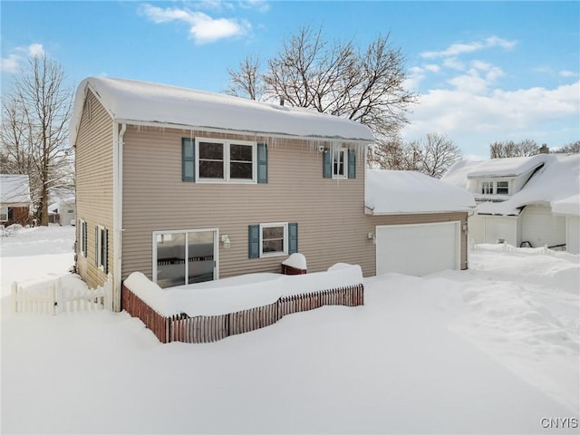 snow covered back of property featuring a garage