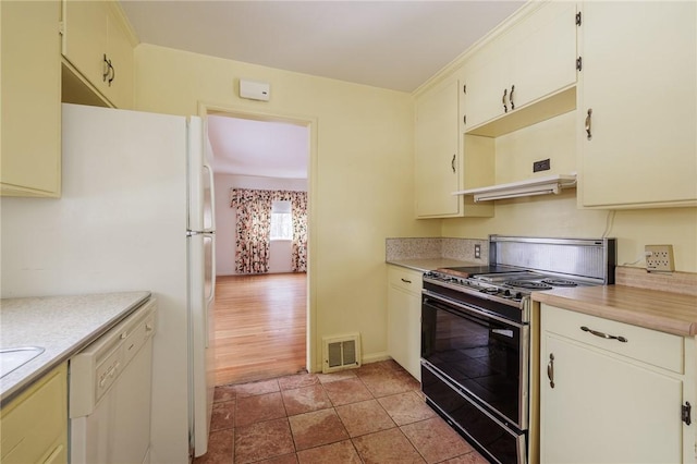 kitchen with black range, white fridge, and light tile patterned flooring