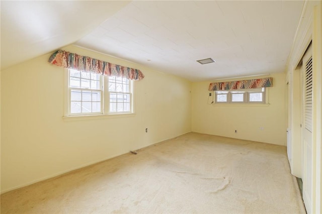 unfurnished bedroom featuring multiple windows, vaulted ceiling, and light colored carpet