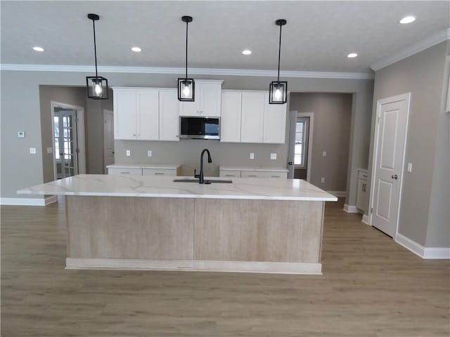 kitchen featuring white cabinetry, sink, and an island with sink