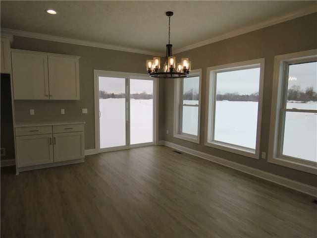 unfurnished dining area with crown molding, plenty of natural light, dark hardwood / wood-style flooring, and a chandelier