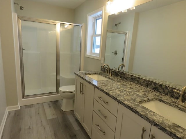 bathroom featuring vanity, toilet, a shower with door, and hardwood / wood-style floors