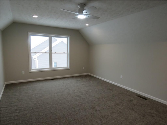 additional living space with ceiling fan, lofted ceiling, a textured ceiling, and dark carpet