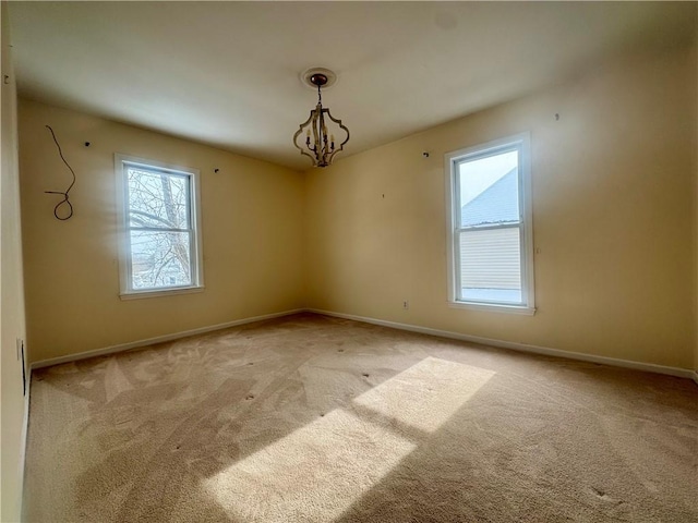 unfurnished room featuring light colored carpet, plenty of natural light, and a notable chandelier