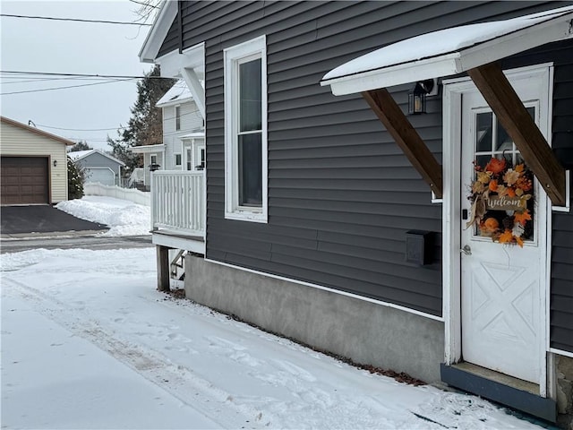 snow covered property with a garage and an outdoor structure