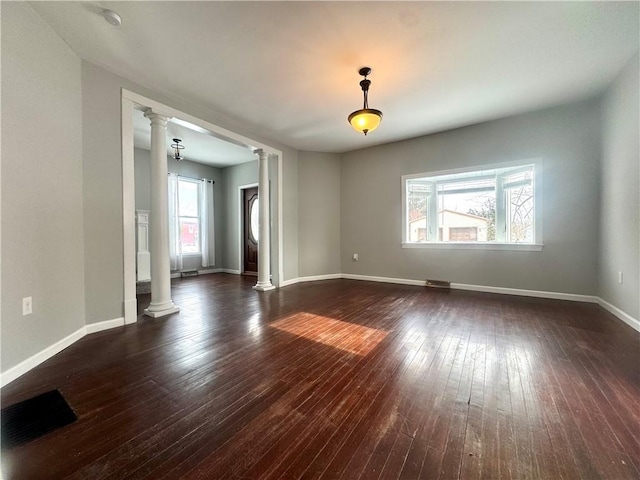 empty room featuring dark wood-type flooring and decorative columns