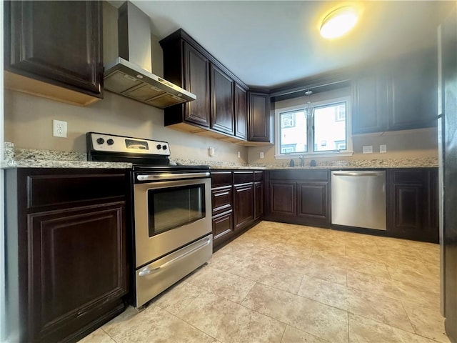 kitchen featuring light stone countertops, appliances with stainless steel finishes, dark brown cabinets, and wall chimney exhaust hood