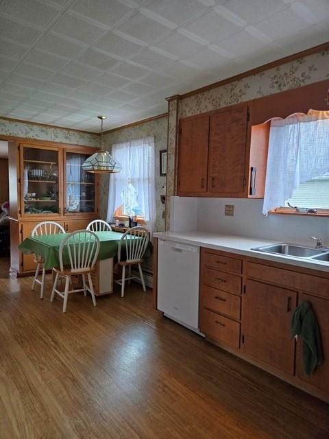 kitchen with decorative light fixtures, sink, ornamental molding, white dishwasher, and hardwood / wood-style floors