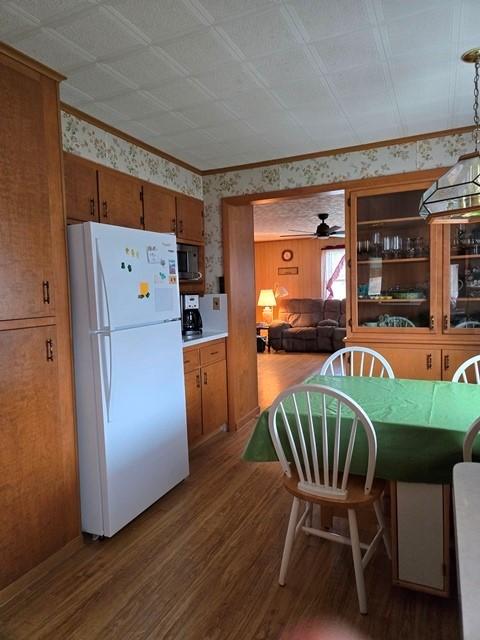 kitchen with pendant lighting, white refrigerator, ceiling fan, crown molding, and hardwood / wood-style flooring