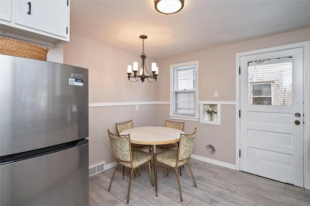 dining space with a chandelier and light wood-type flooring