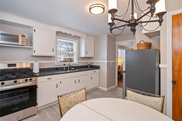 kitchen with light wood-type flooring, appliances with stainless steel finishes, sink, and white cabinets