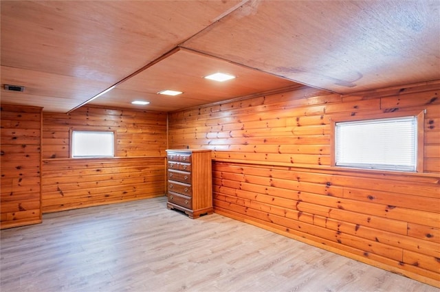 additional living space with light hardwood / wood-style floors and wood walls