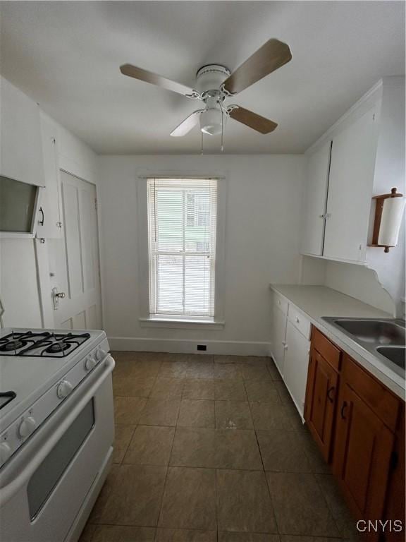 kitchen with sink, tile patterned flooring, white gas stove, and white cabinets