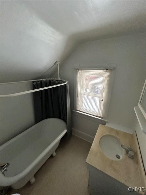 bathroom with lofted ceiling, a tub to relax in, and vanity