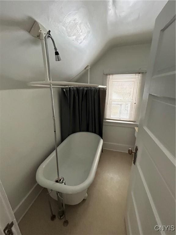 bathroom with vaulted ceiling and a tub to relax in