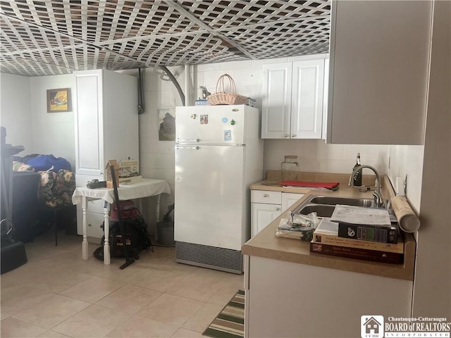 kitchen featuring sink, light tile patterned floors, white cabinets, and white refrigerator