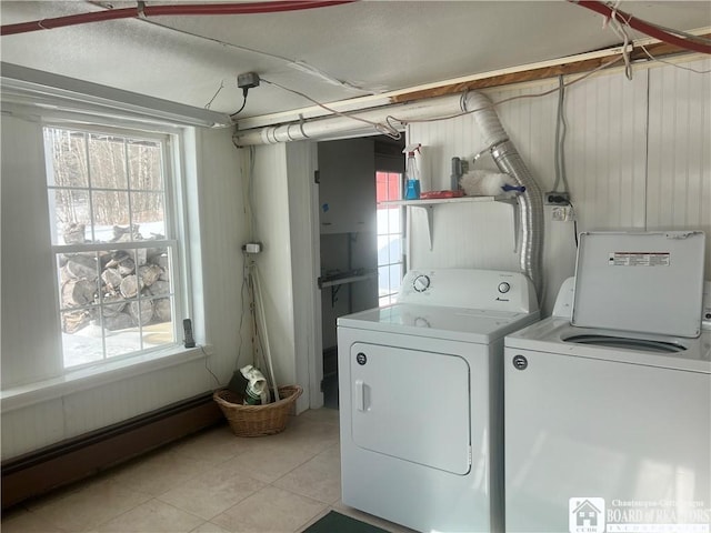 clothes washing area featuring a baseboard radiator, washer and dryer, a healthy amount of sunlight, and light tile patterned flooring