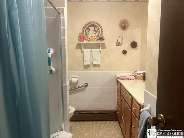 bathroom with tile walls, vanity, toilet, and a shower