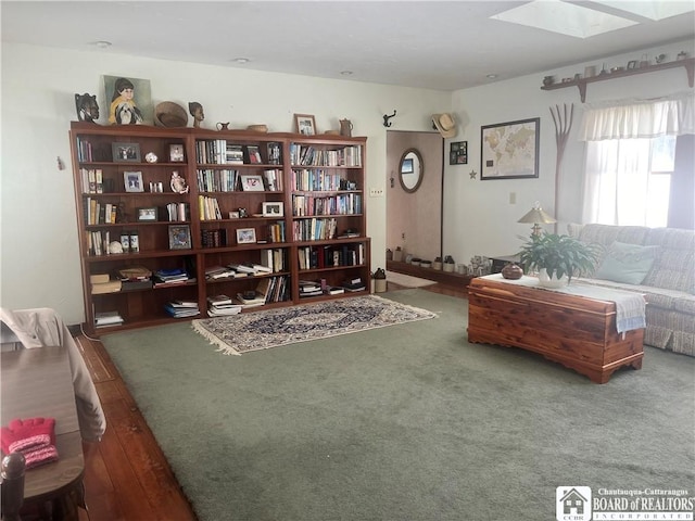 sitting room with dark wood-type flooring and a skylight