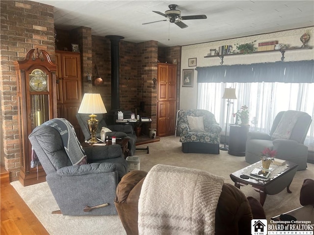 living room with ceiling fan, brick wall, and a wood stove