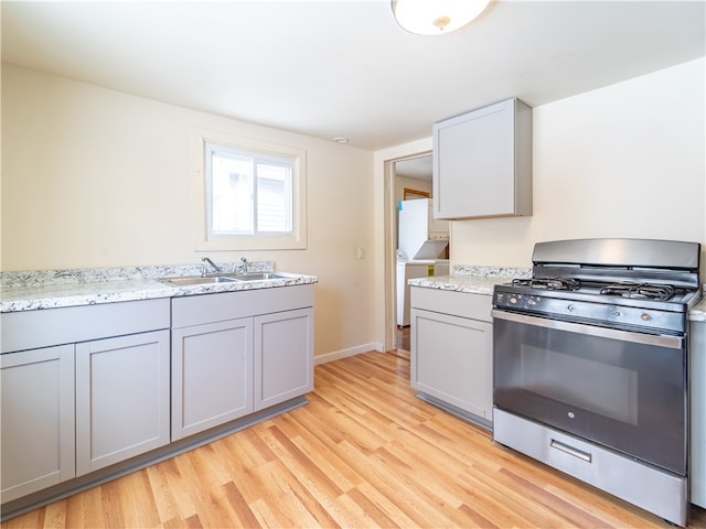 kitchen with light hardwood / wood-style floors, gray cabinets, stainless steel gas range, and sink