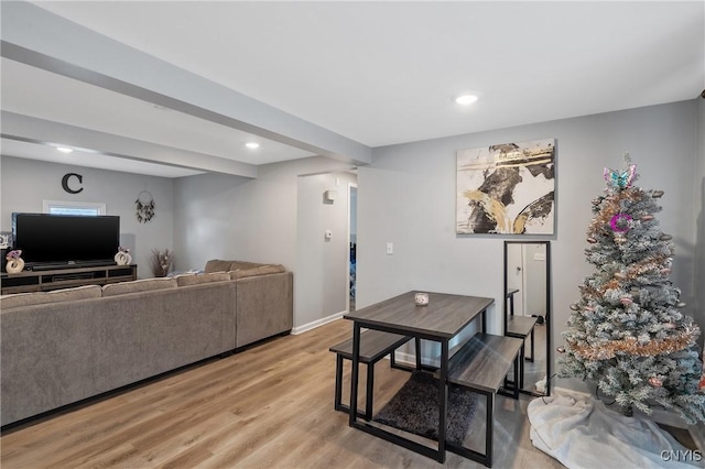 living room featuring beam ceiling and light hardwood / wood-style flooring