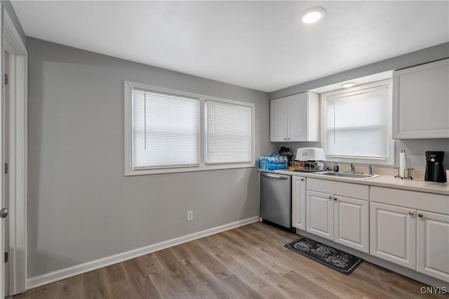 kitchen with stainless steel dishwasher, light hardwood / wood-style floors, sink, and white cabinets