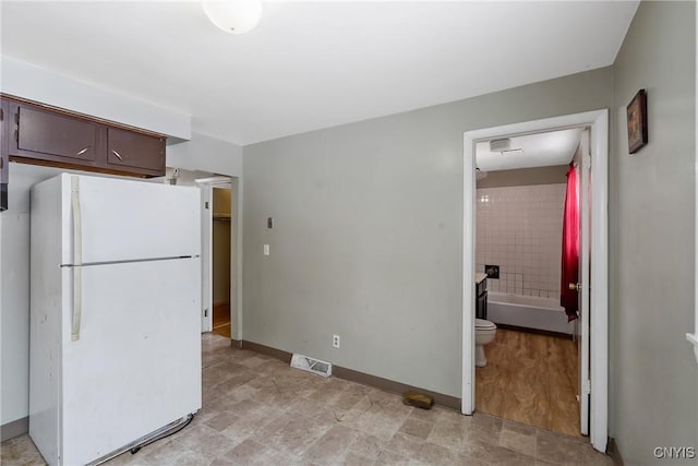 kitchen featuring white refrigerator and dark brown cabinets