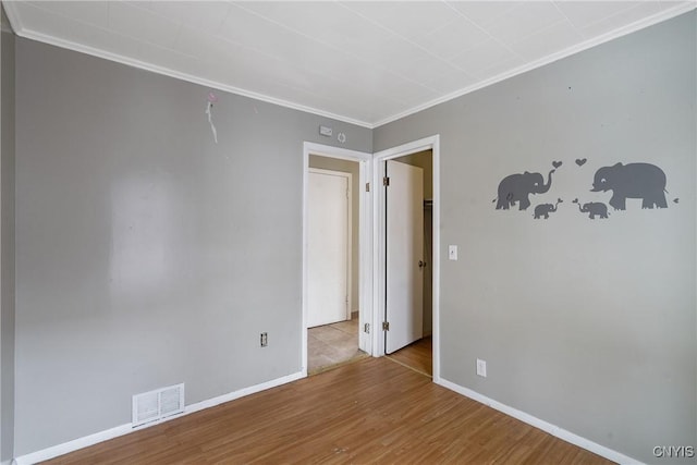 spare room with ornamental molding and light hardwood / wood-style floors