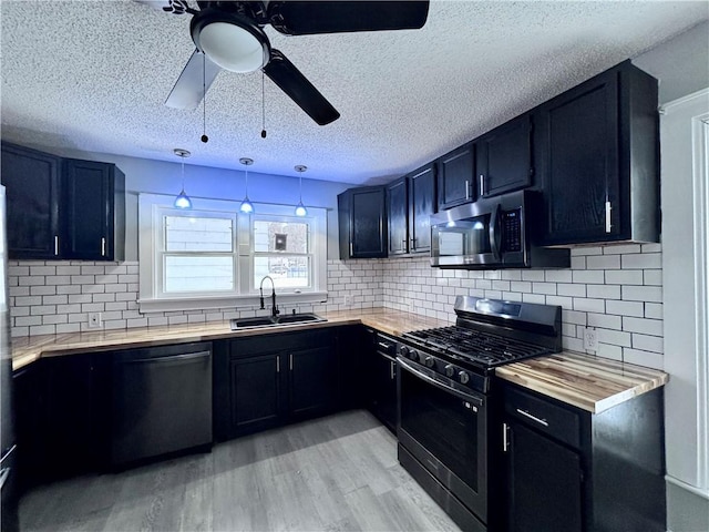 kitchen featuring sink, hanging light fixtures, stainless steel appliances, decorative backsplash, and light wood-type flooring