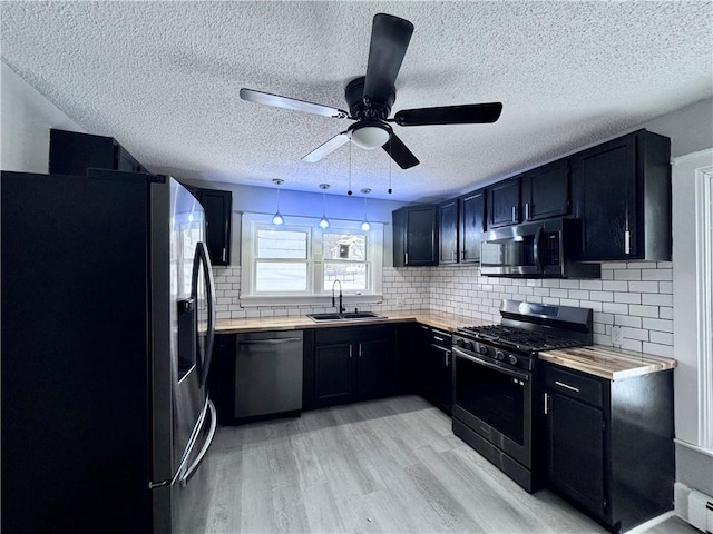 kitchen with sink, hanging light fixtures, a baseboard heating unit, stainless steel appliances, and light hardwood / wood-style floors